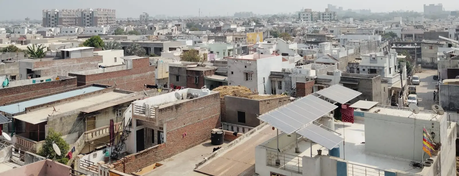 Small rooftop solar panel array installed on a home in a dense Indian residential neighbourhood
